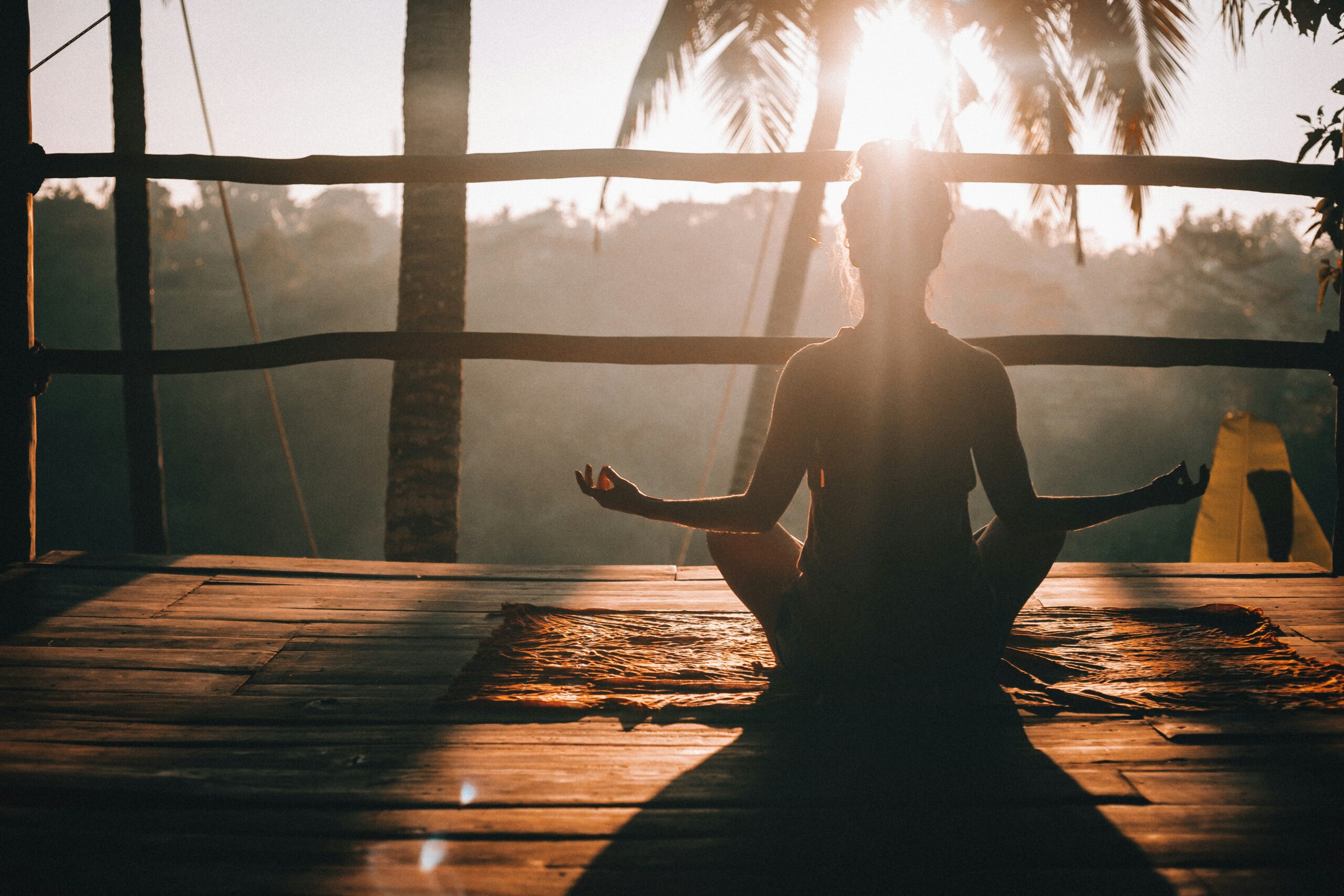wellness Woman meditating at sunrise.